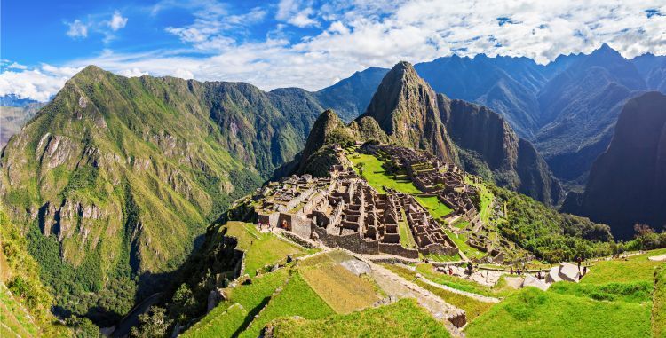 An aerial view of the ruins of machu picchu in the middle of a mountain range.