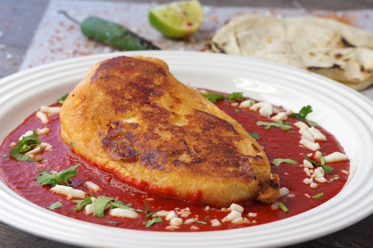 A white plate topped with a stuffed pepper  and sauce