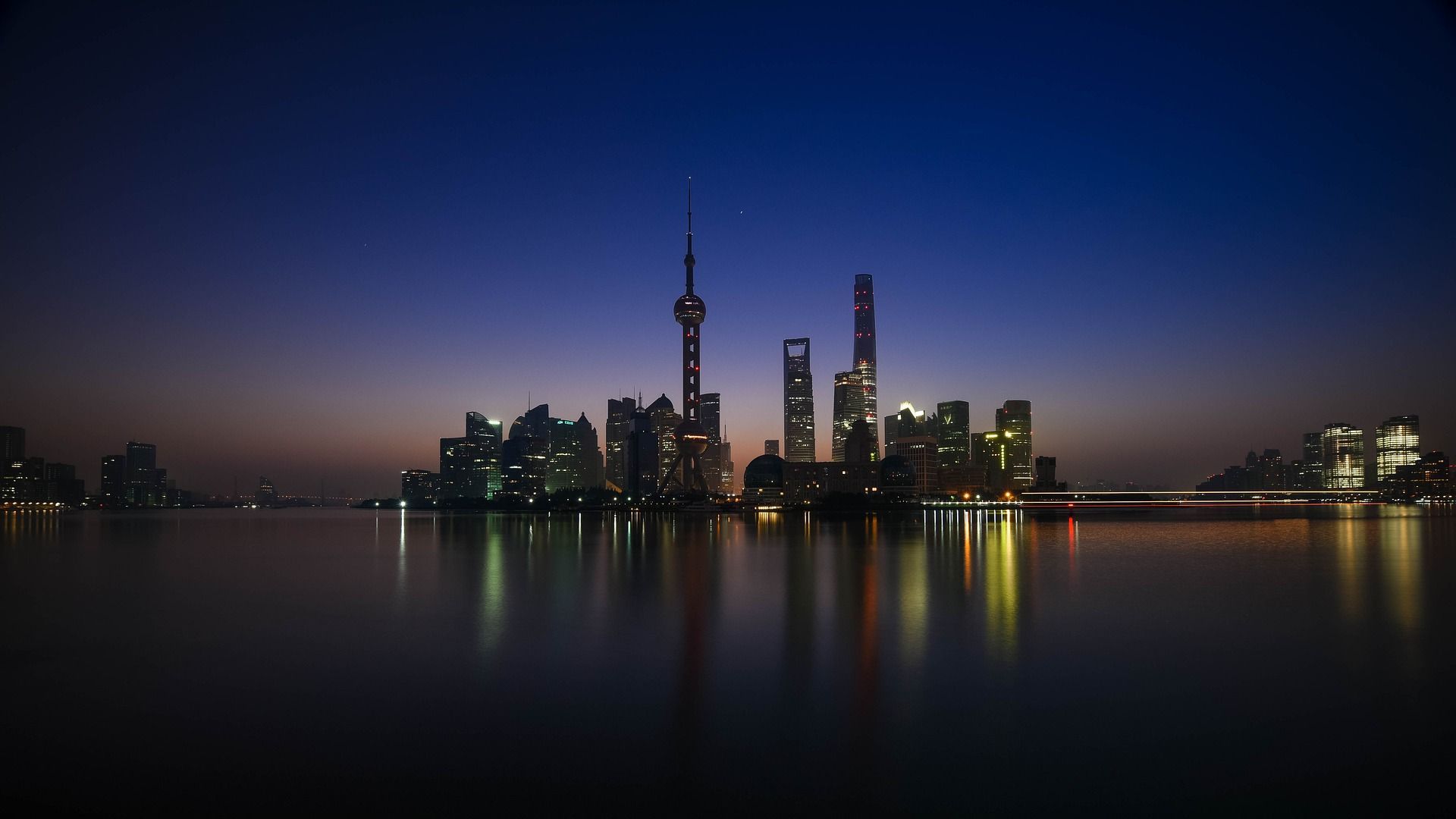 A city skyline is reflected in the water at night in Shanghai