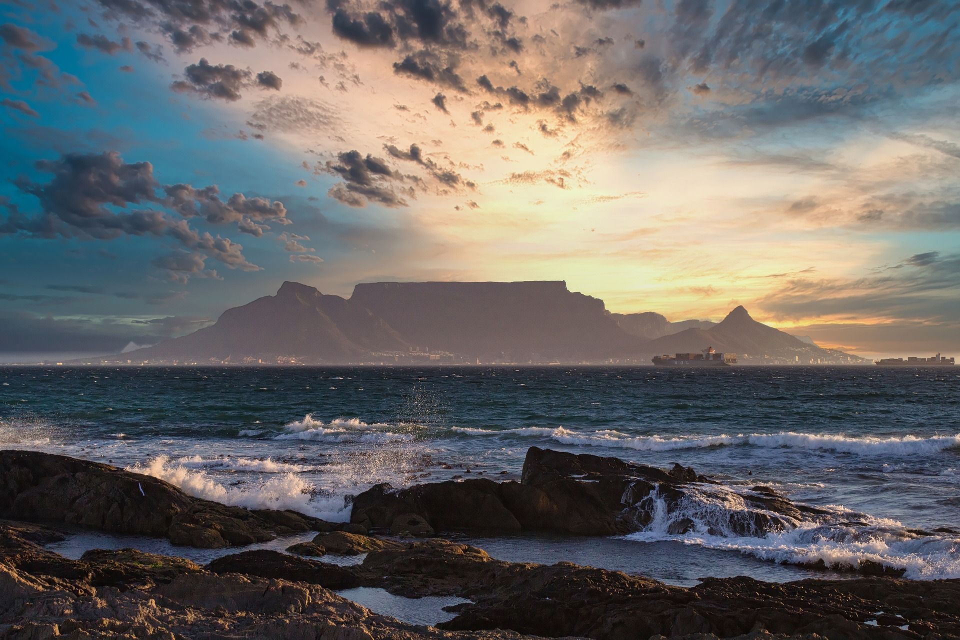 A sunset over a body of water with a mountain in the background.