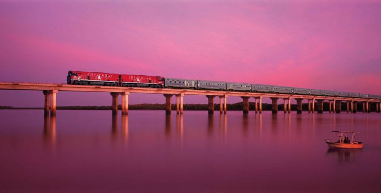 A train is going over a bridge over a body of water.