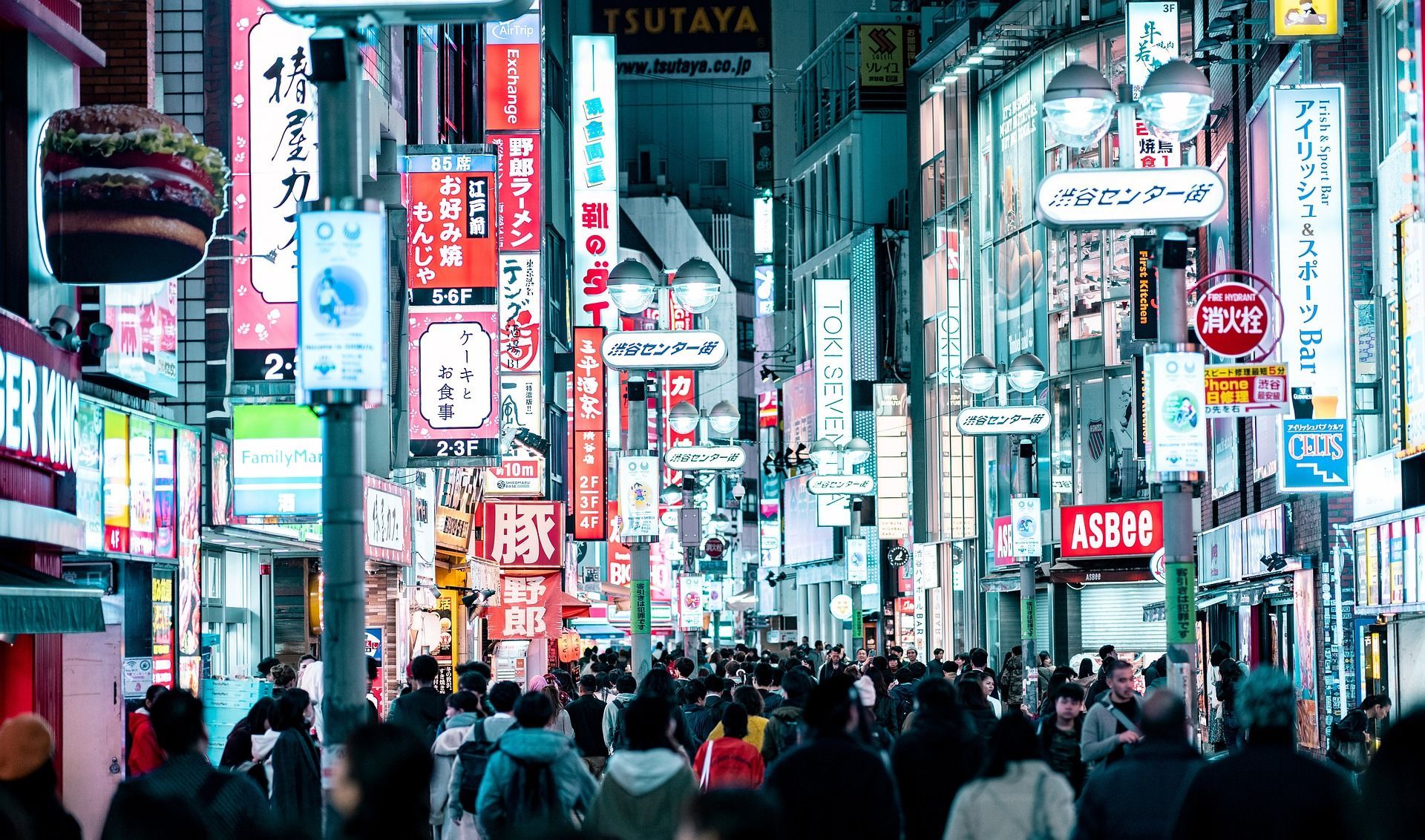 A crowd of people are walking down a busy city street at night in Tokyo