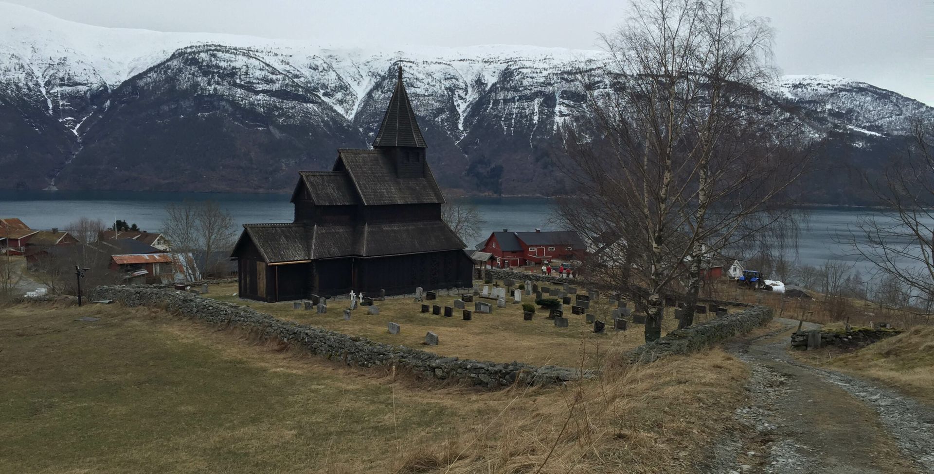 A church sitting on top of a hill next to a lake with mountains in the background.