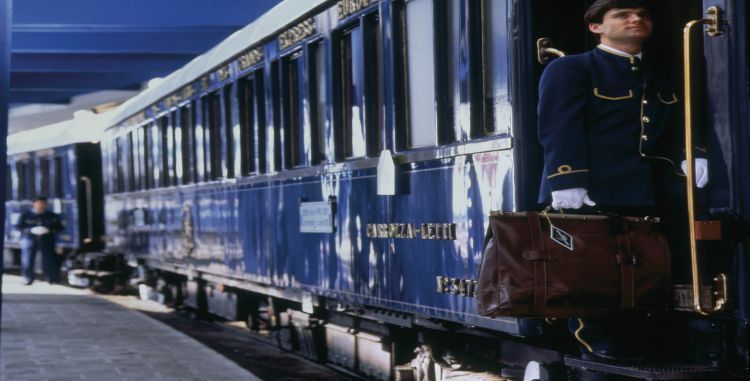A man with a suitcase is standing next to a train.