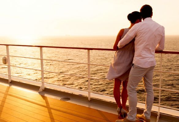 a man and a woman are standing on the deck of a cruise ship looking at the ocean . The Retired Traveller