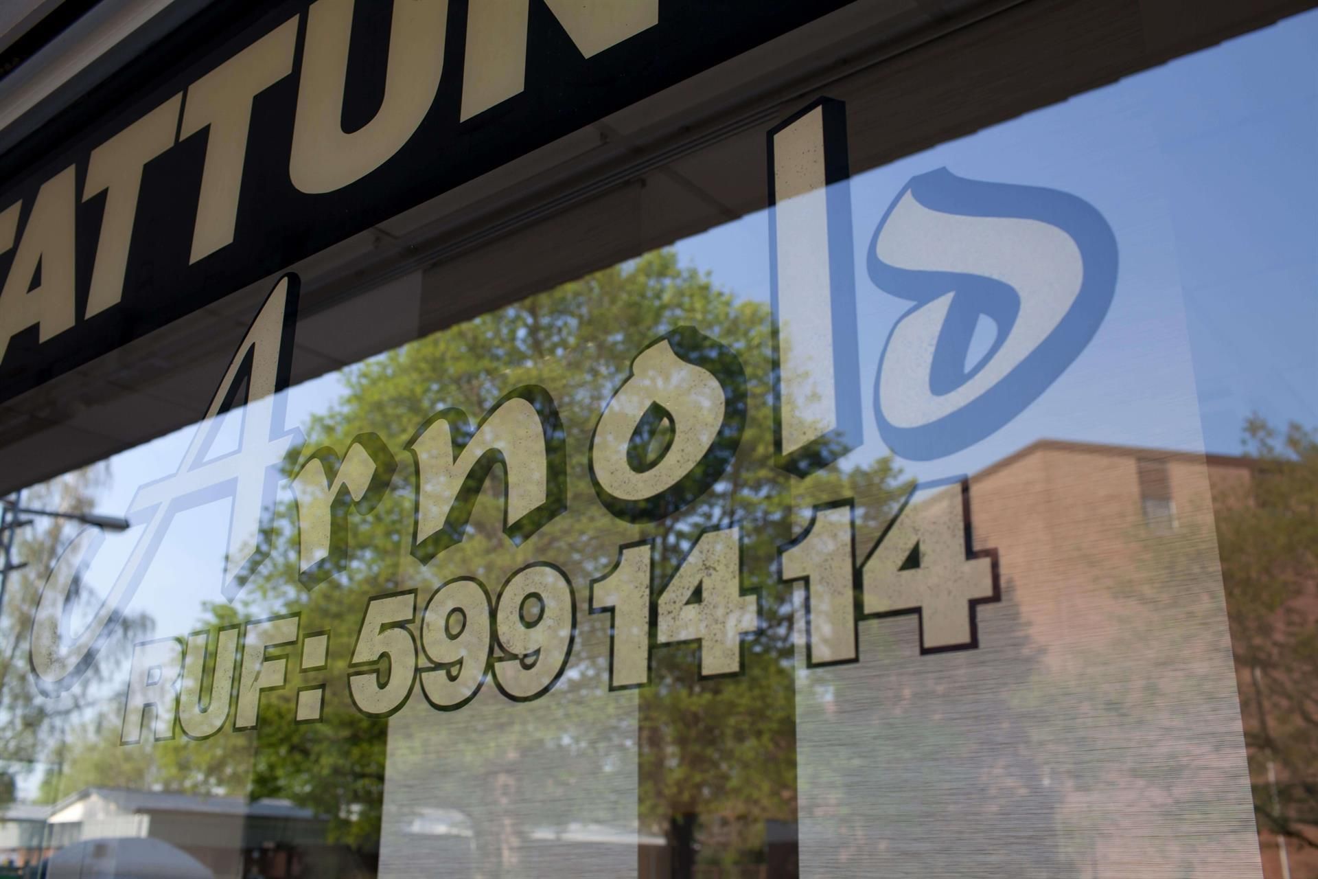 Eine Spiegelung eines Gebäudes und von Bäumen in einem Schaufenster