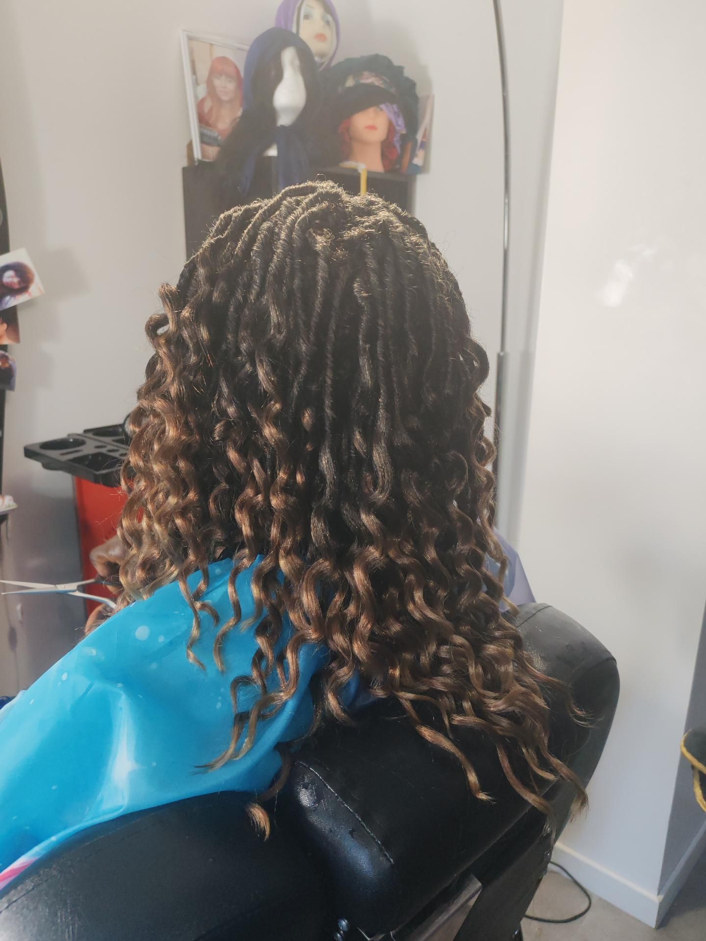 Personne avec des dreadlocks brunes et blondes, assise dans un fauteuil de salon.