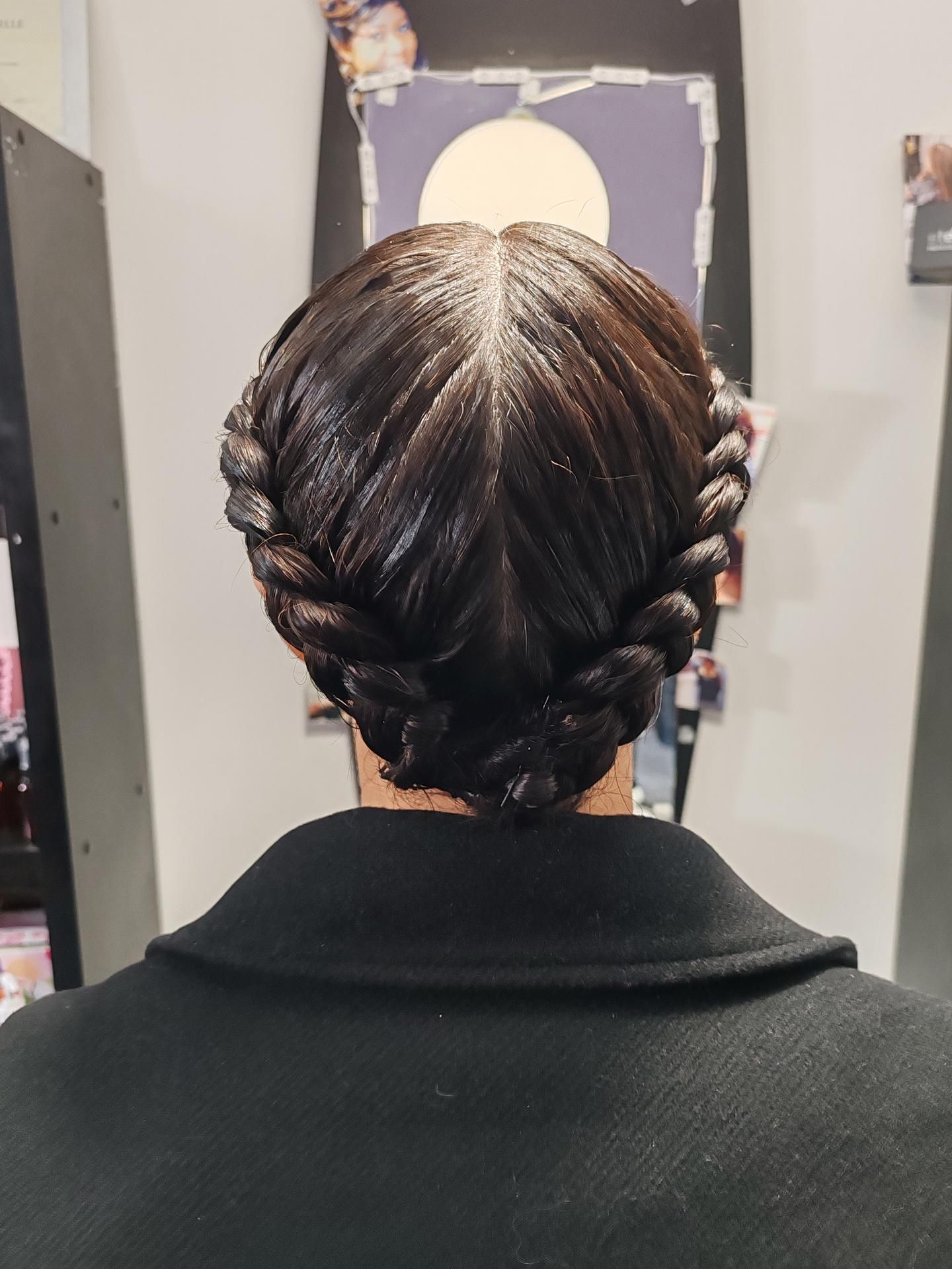 Personne aux cheveux foncés coiffés en deux couronnes tressées.