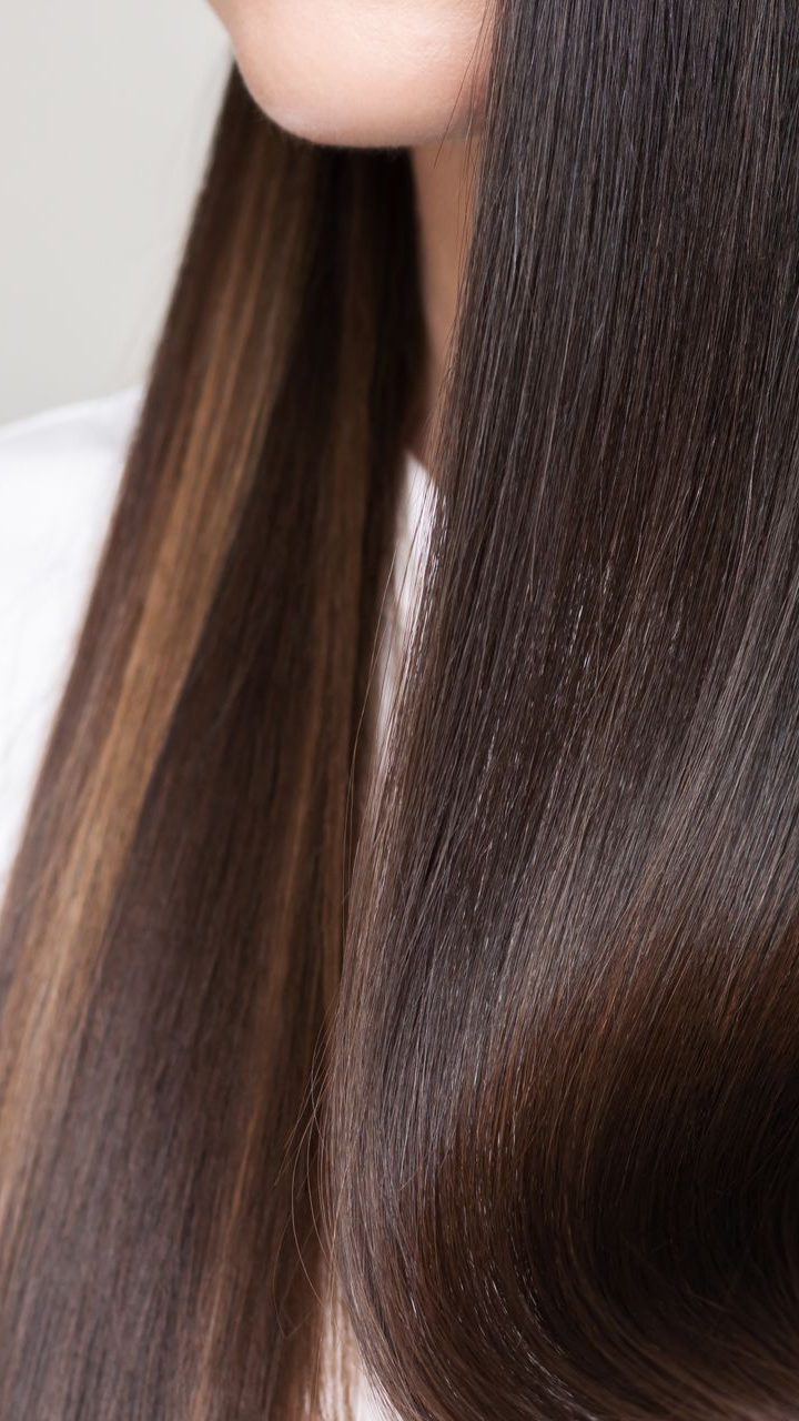 Gros plan sur des cheveux raides, brun foncé avec des reflets brun clair.