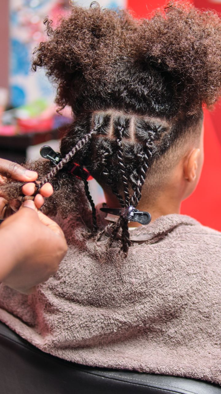 Coiffure avec des torsades et des mains lui tressant les cheveux.