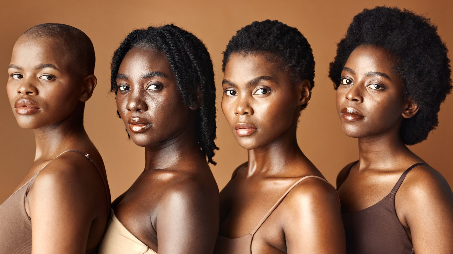 Quatre personnes à la peau foncée posent, arborant des coiffures variées et portant des hauts sur un fond marron.