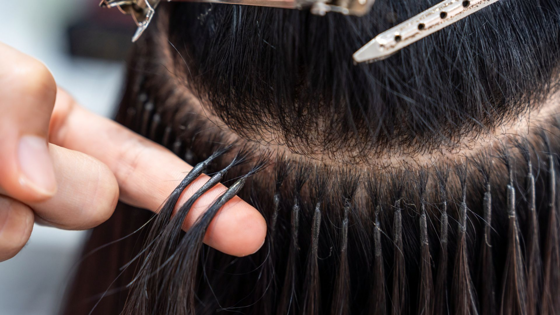 Gros plan sur la pose d'extensions capillaires.