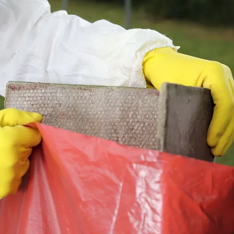 Una persona que lleva guantes amarillos sostiene un trozo de madera.