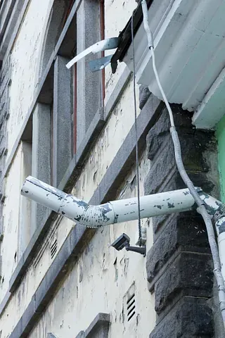 Un tubo blanco cuelga del costado de un edificio.