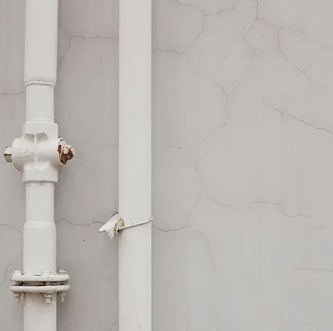 Un tubo blanco está unido a una pared blanca.