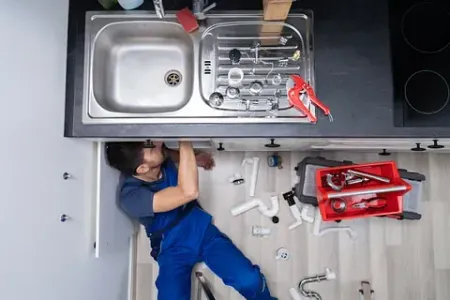 Un fontanero está arreglando un fregadero en una cocina.