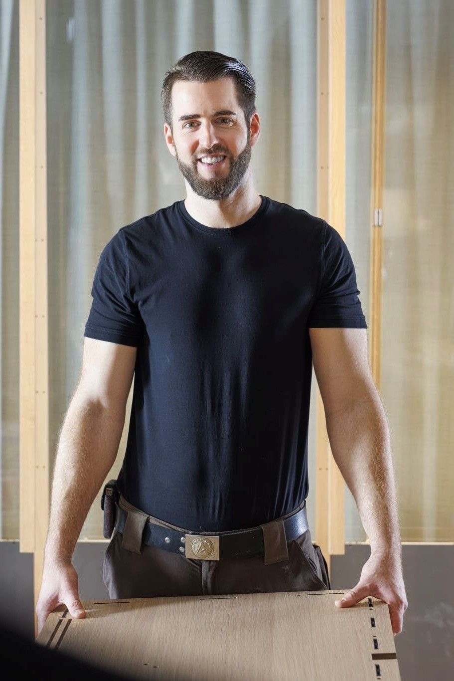 Ein Mann mit Bart hält einen Karton.