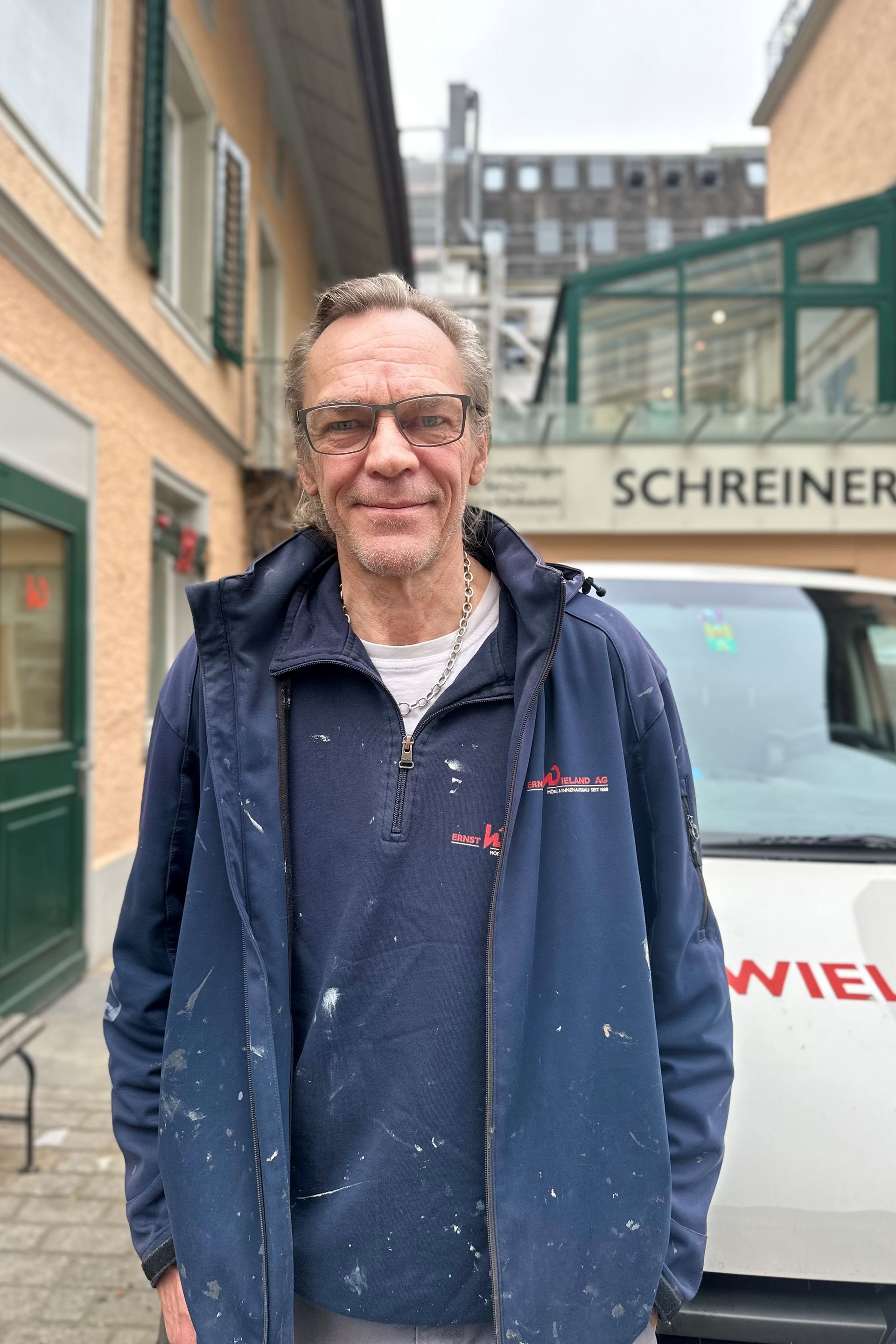 Ein Mann steht vor einem Schild mit der Aufschrift „Schrinerei“