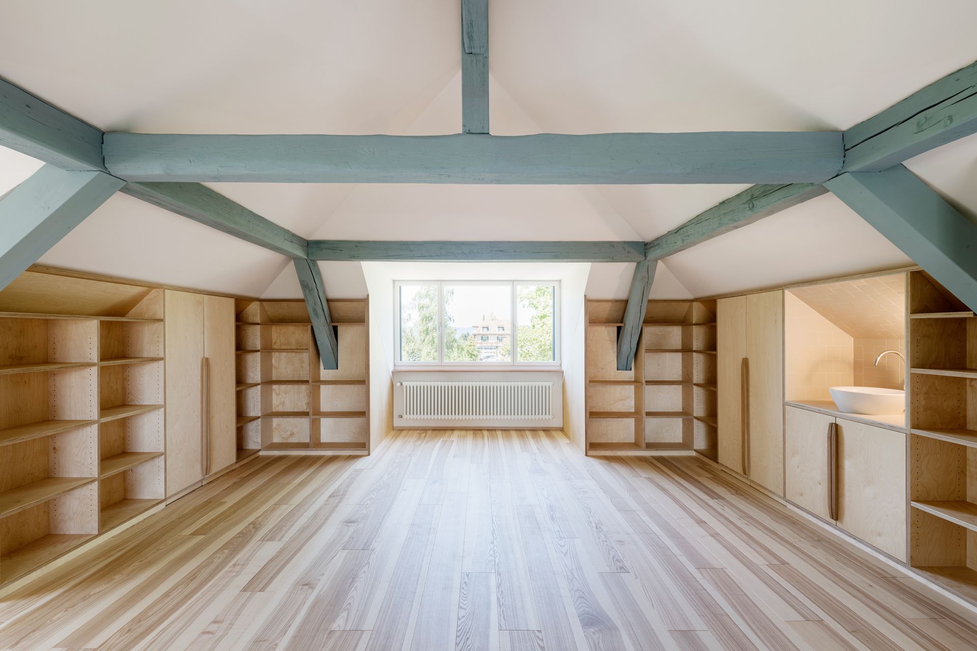 Ein großer leerer Raum mit Holzboden und Regalen.