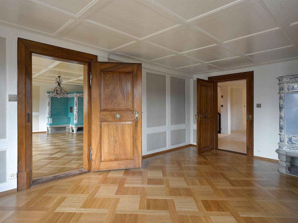 Ein leerer Raum mit Holzboden und zwei Türen.