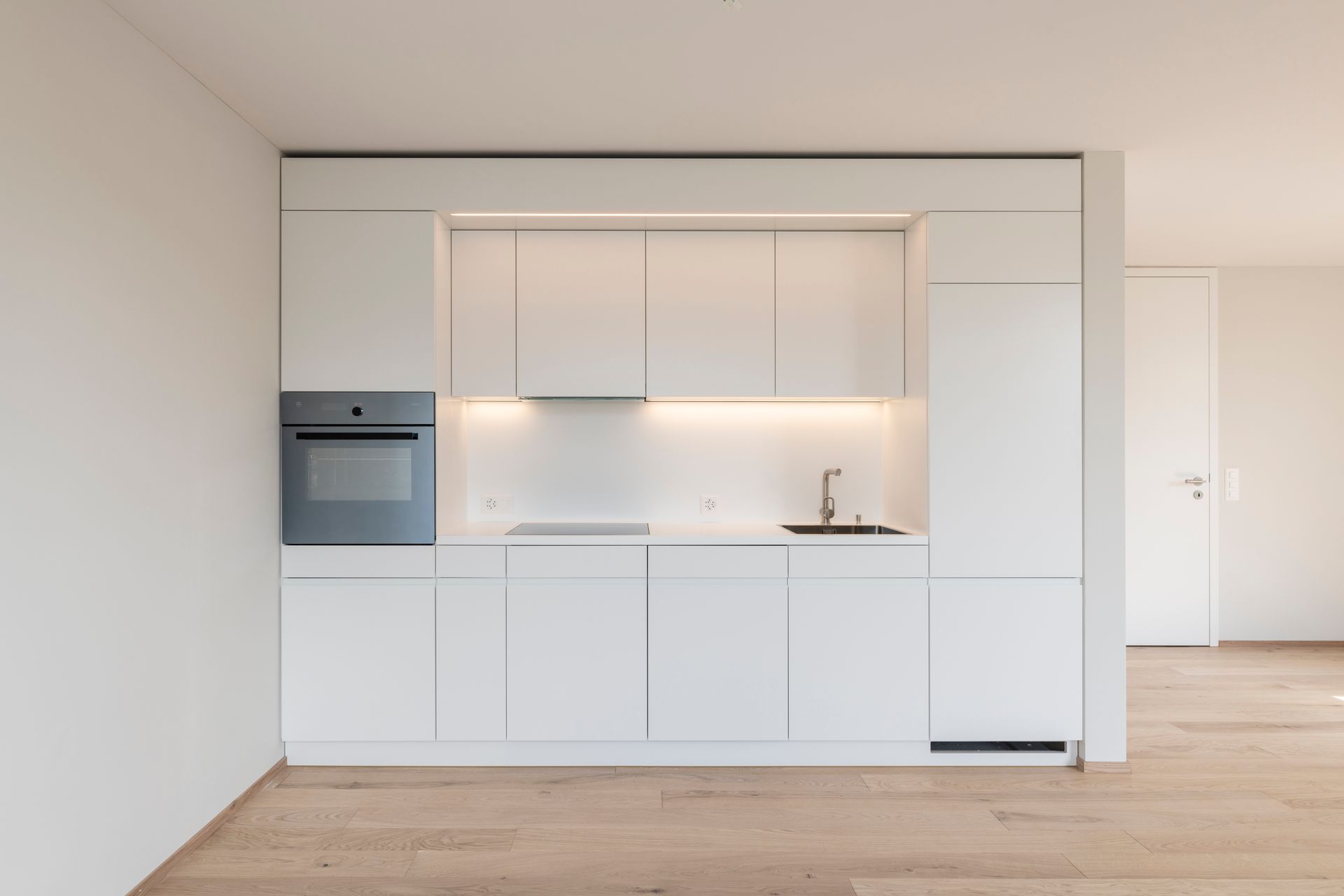 Eine leere Küche mit weißen Schränken und Holzböden