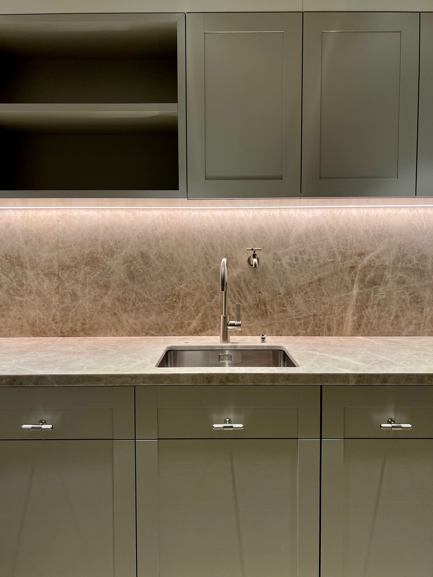 Eine Küche mit Spüle, Schränken und einer Marmorarbeitsplatte.