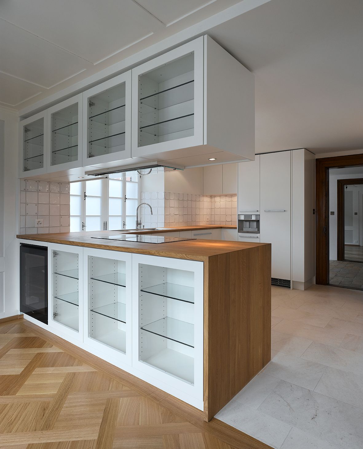Eine Küche mit weißen Schränken und Glastüren