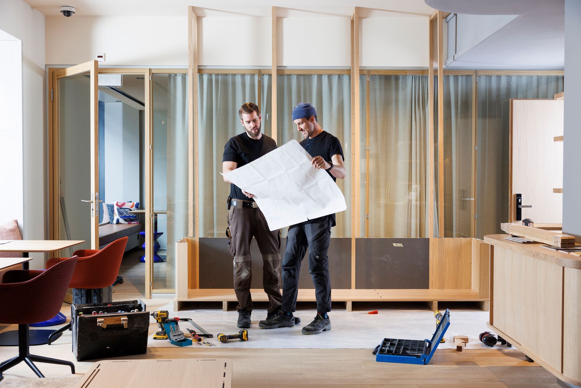 Zwei Männer stehen in einem Raum und schauen sich einen Bauplan an.