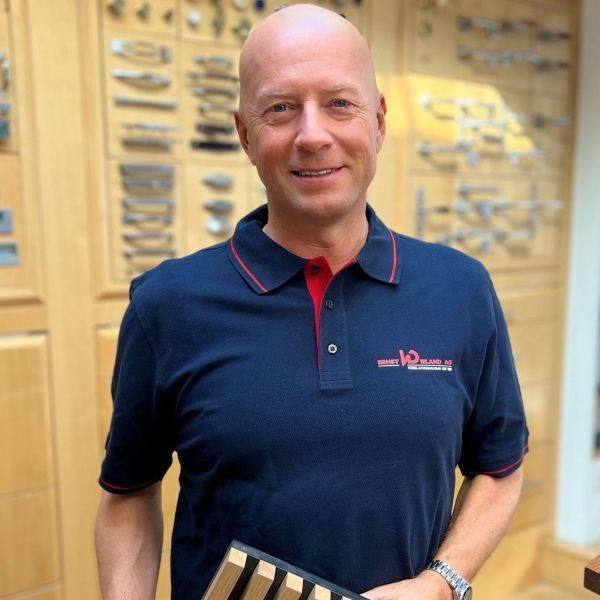 Ein kahlköpfiger Mann, der ein blaues Hemd mit dem Wort v2 darauf trägt