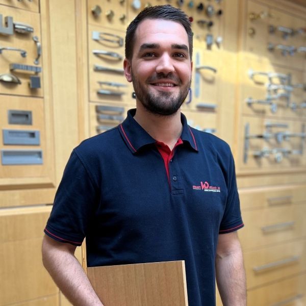 Ein Mann hält ein Stück Holz vor einer Wand aus Griffen