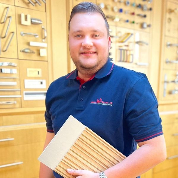 Ein Mann in einem blauen Hemd hält ein Stück Holz