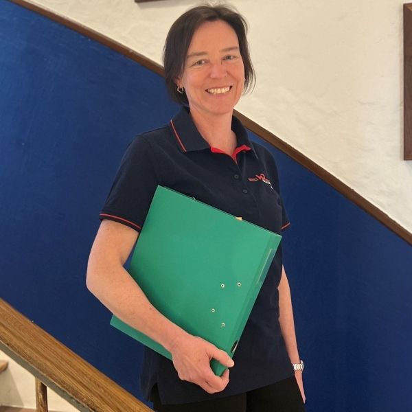 Eine Frau im blauen Hemd hält einen grünen Ordner