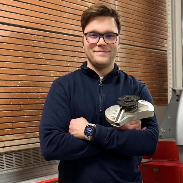 Ein Mann mit Brille und Uhr hält eine Maschine