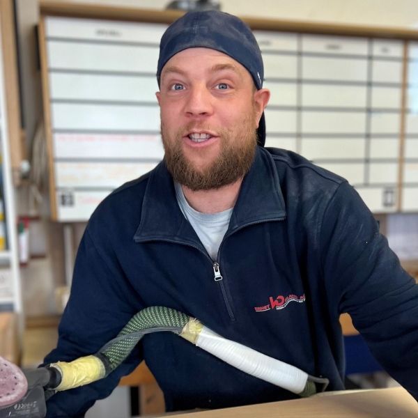 Ein Mann mit Bart trägt einen Hut und eine blaue Jacke