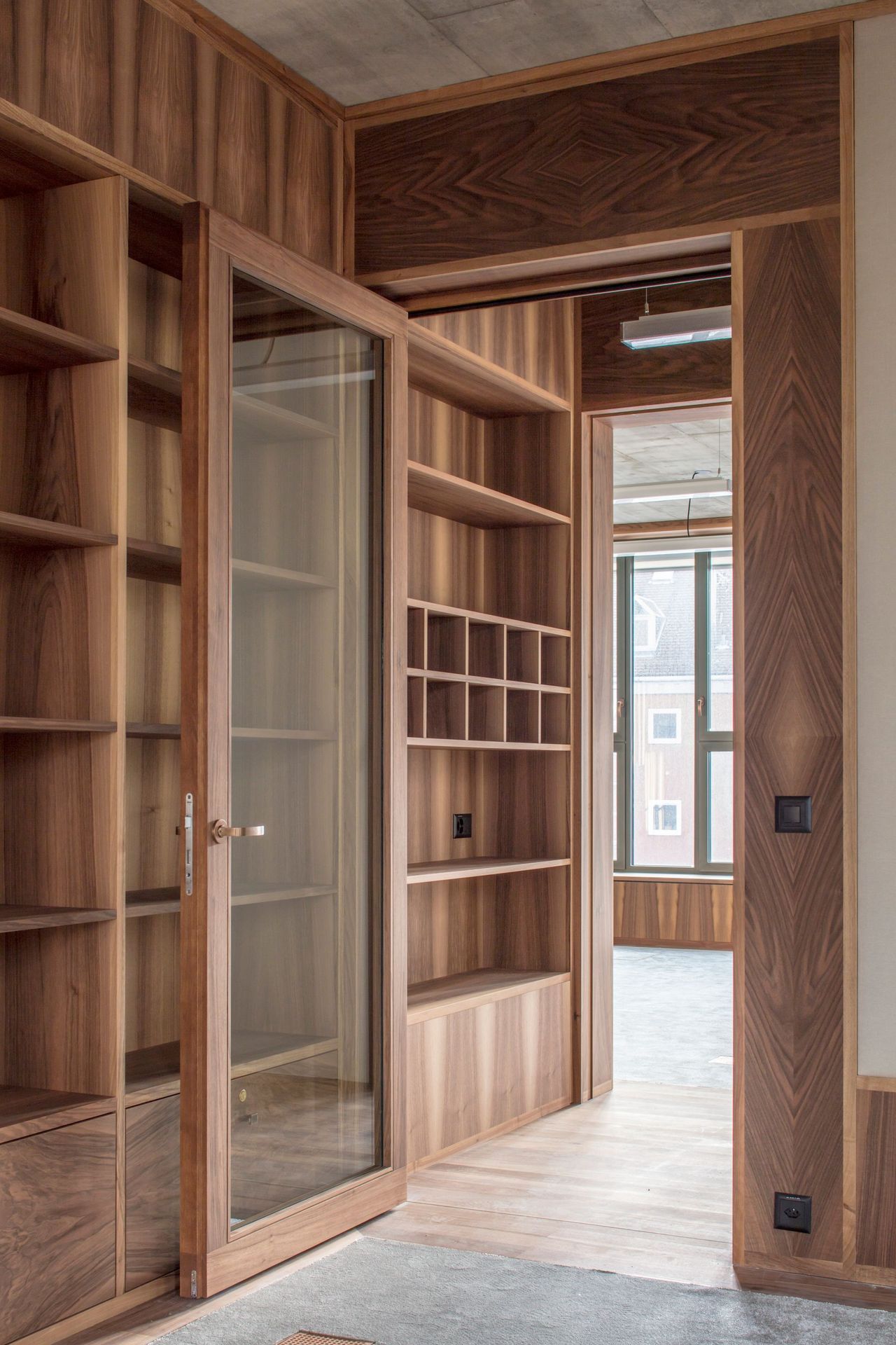 Ein Raum mit Holzregalen und einer Glastür.