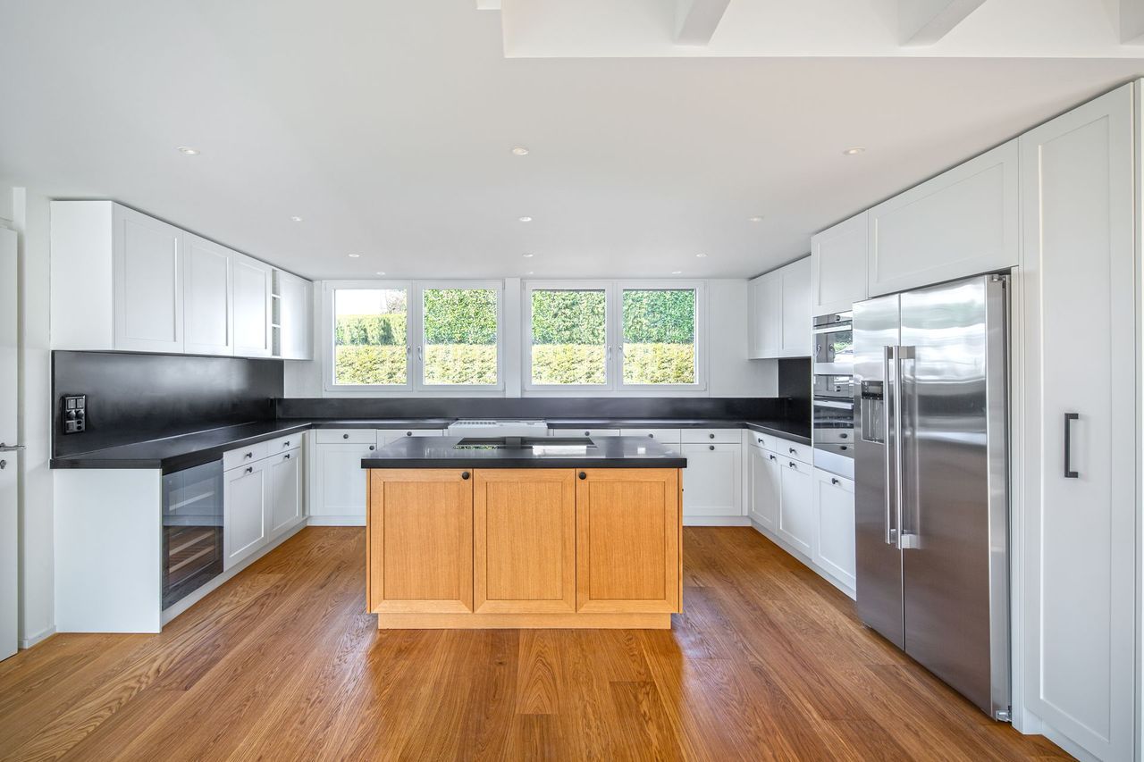 Eine Küche mit weißen Schränken, Geräten aus Edelstahl und einer Holzinsel.