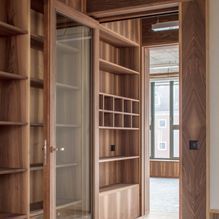 Ein Flur mit Holzregalen und Glastüren, die zu einem Zimmer führen.