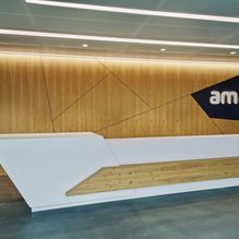 Ein moderner Rezeptionstresen mit einer Holzwand dahinter.