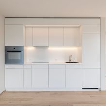 Eine Küche mit weißen Schränken, einer Spüle, einem Herd und einem Ofen.