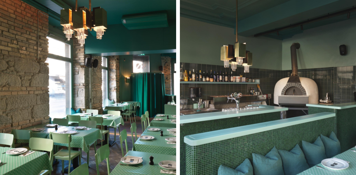 Ein Restaurant mit grünen Tischen und Stühlen und einem Pizzaofen.