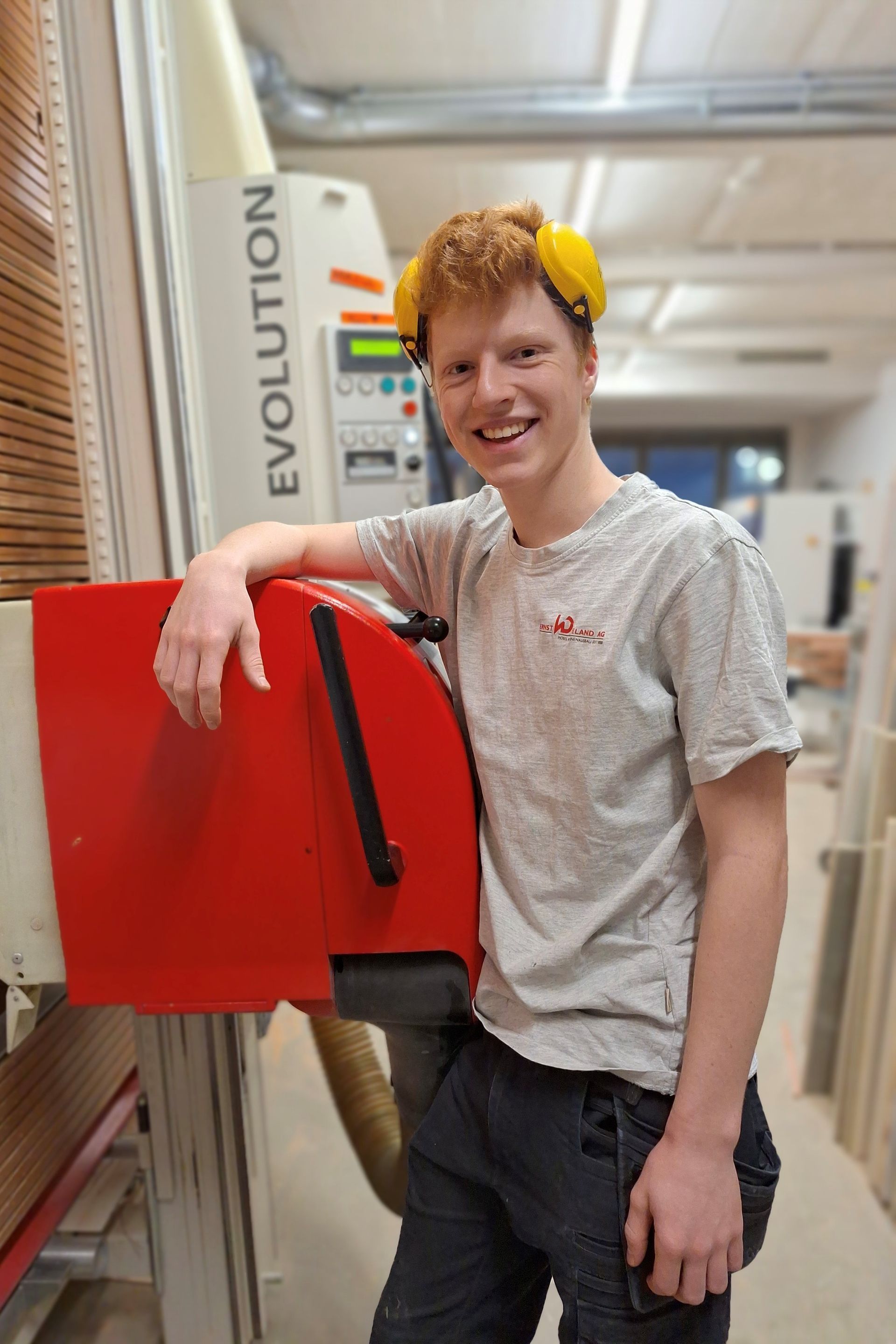 Ein junger Mann steht vor einer Maschine in einer Fabrik.