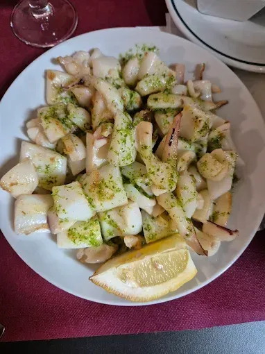 Un plato de comida con una rodaja de limón sobre una mesa.