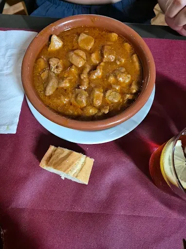 Un plato de comida está sobre una mesa al lado de un trozo de pan.