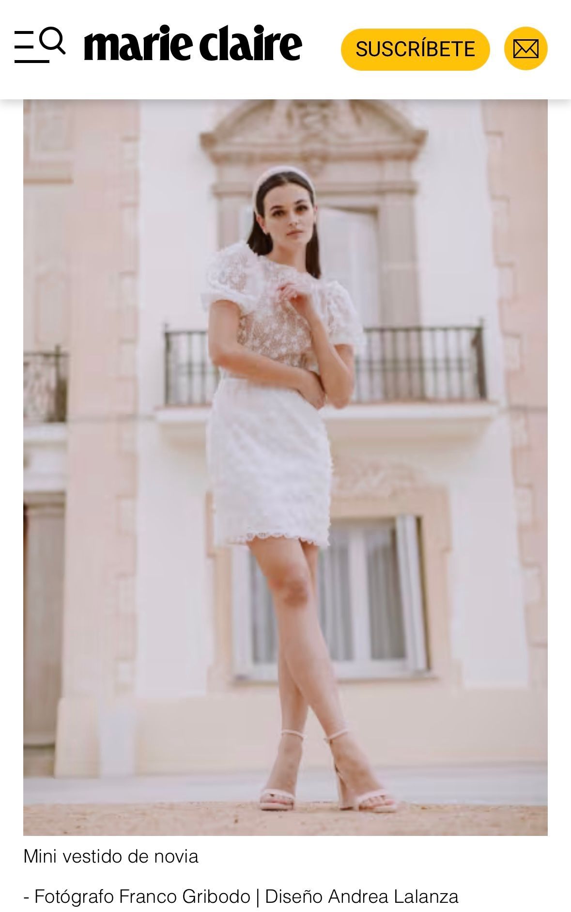 Una mujer con un vestido blanco está parada frente a un edificio.