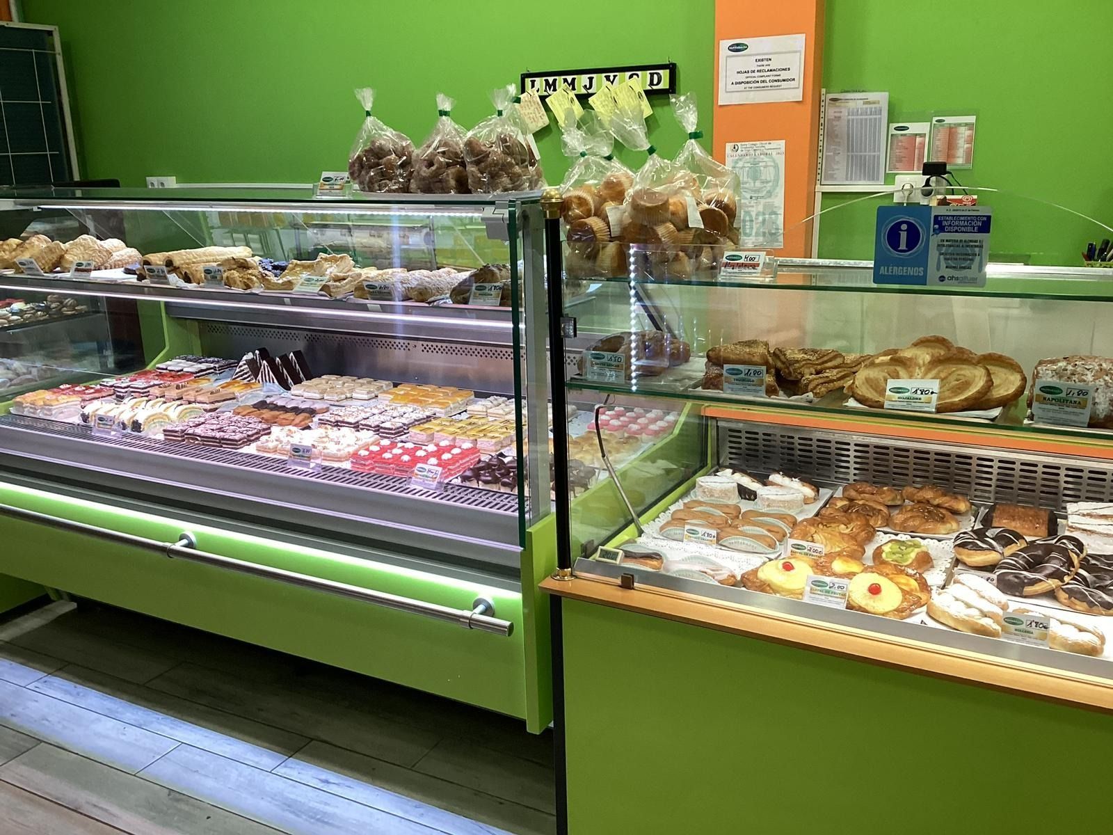 Vitrina de panadería con pasteles y postres en un interior de tienda verde.