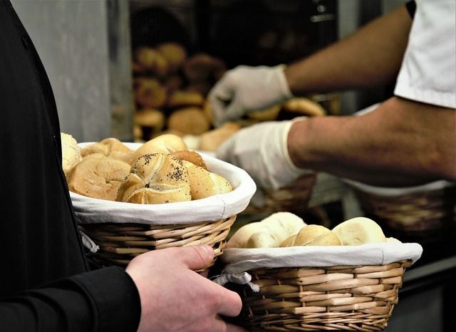 Manos sosteniendo cestas de pan en el mostrador de una panadería.