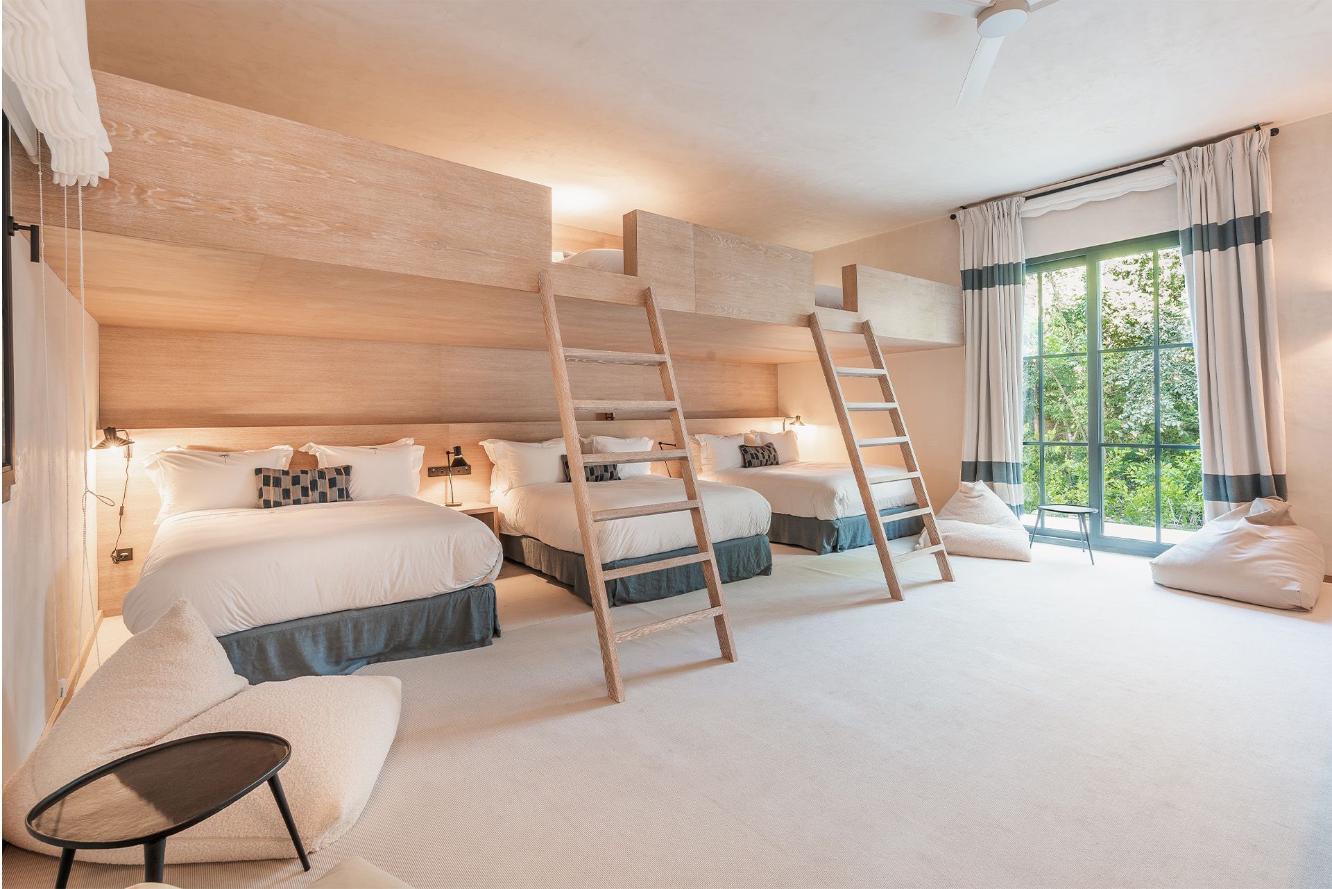 Bright bedroom with three bunk beds, ladder access, and a sliding glass door to a balcony.
