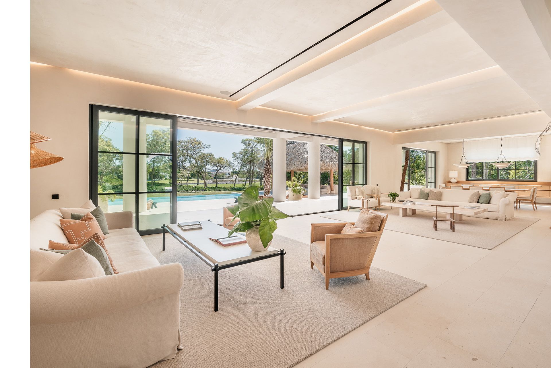Bright, modern living room with cream sofas, glass doors, and a pool view outside