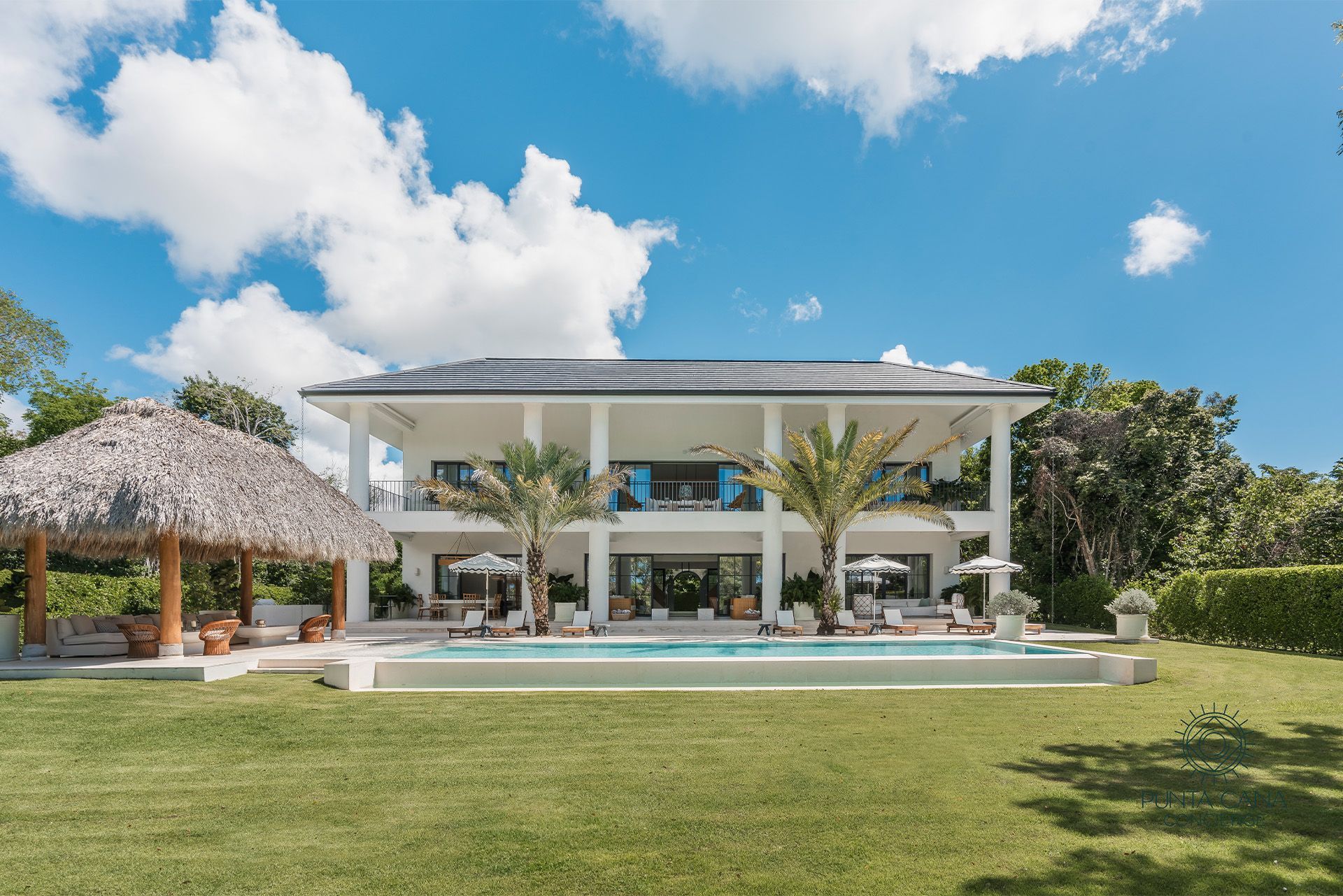 Wooden pergola walkway amid lush tropical greenery leading to a white doorway