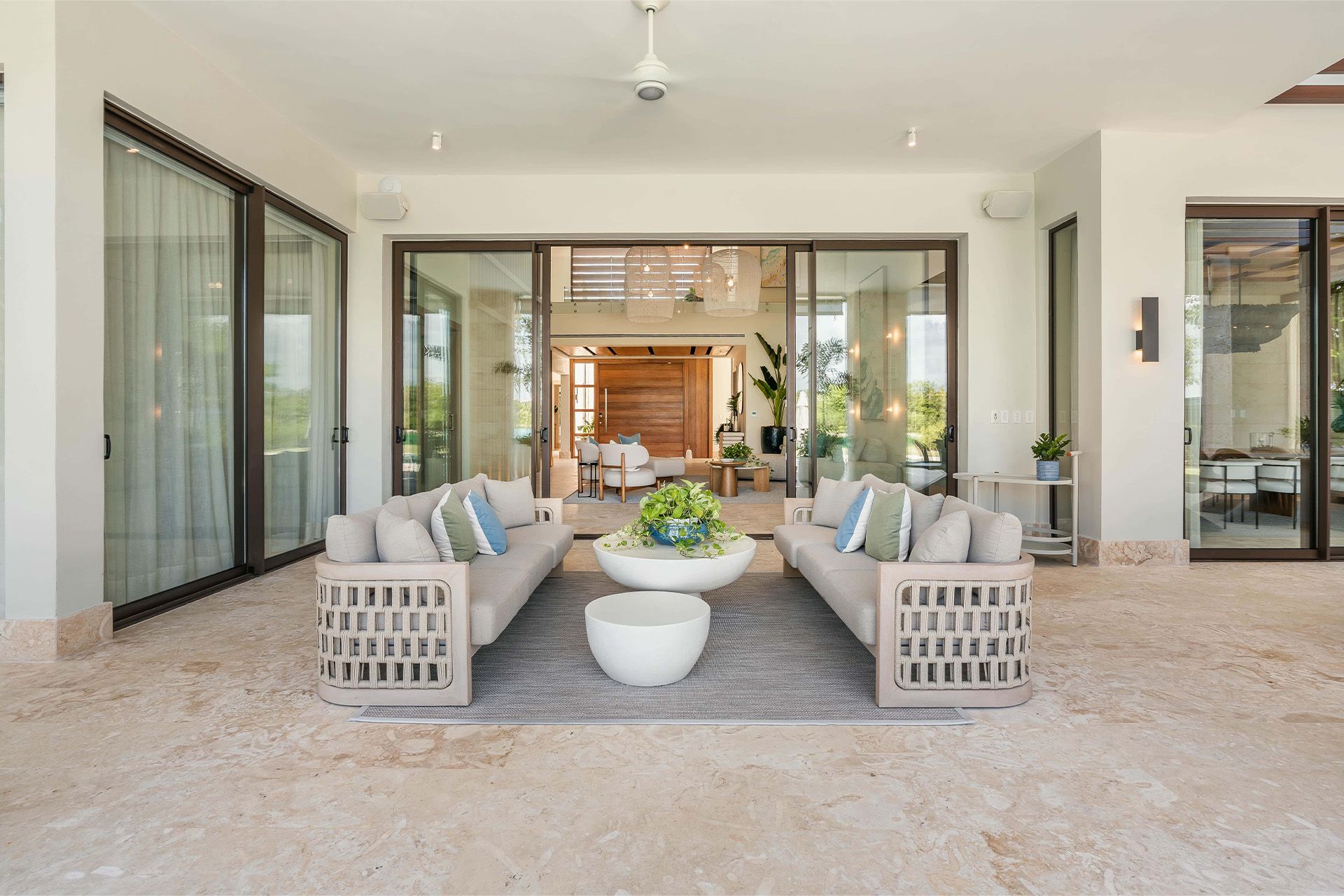 Covered patio with modern seating, a coffee table, and sliding glass doors opening to the home